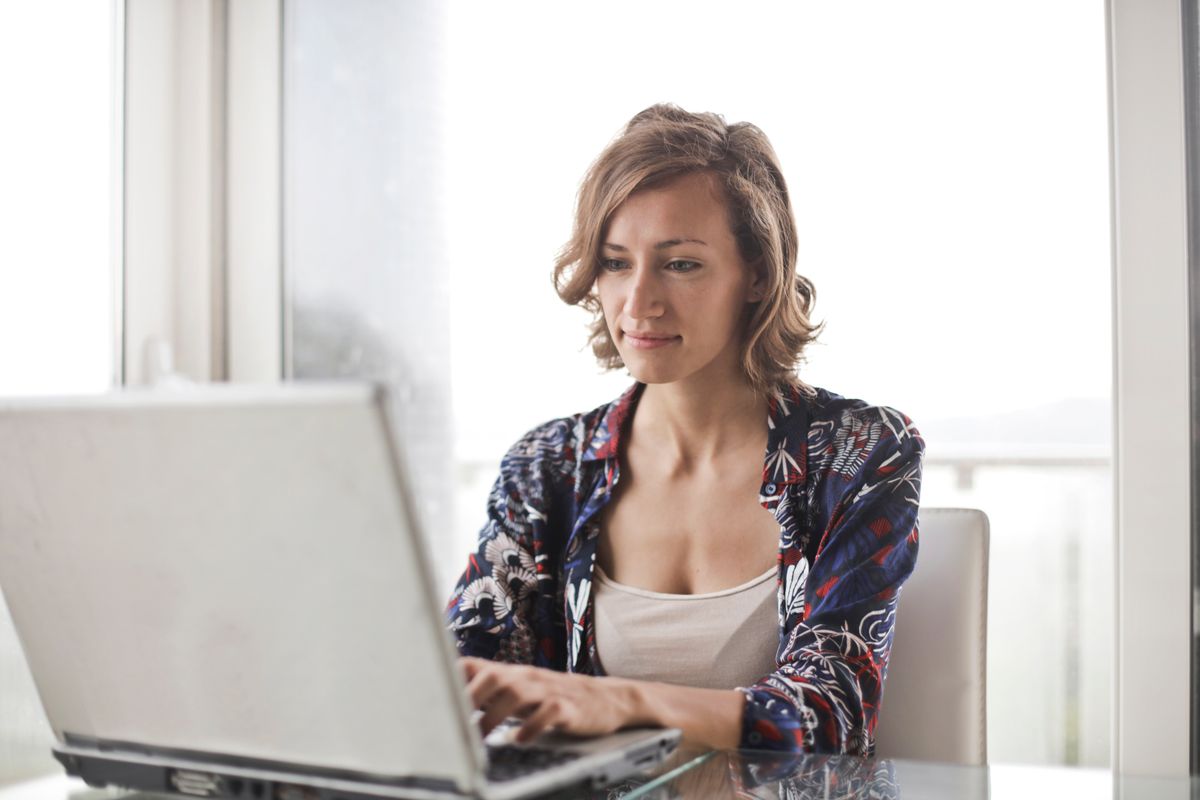 A virtual assistant working at a laptop in a bright home office